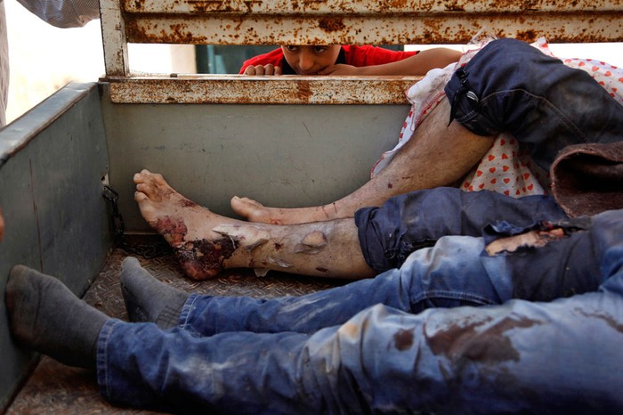 Một cậu bé Syria nhìn vào thùng một chiếc xe tải, nơi chứa 9 xác người lớn Syria bị bắn chết ở Anadan hôm 16/8/2012.