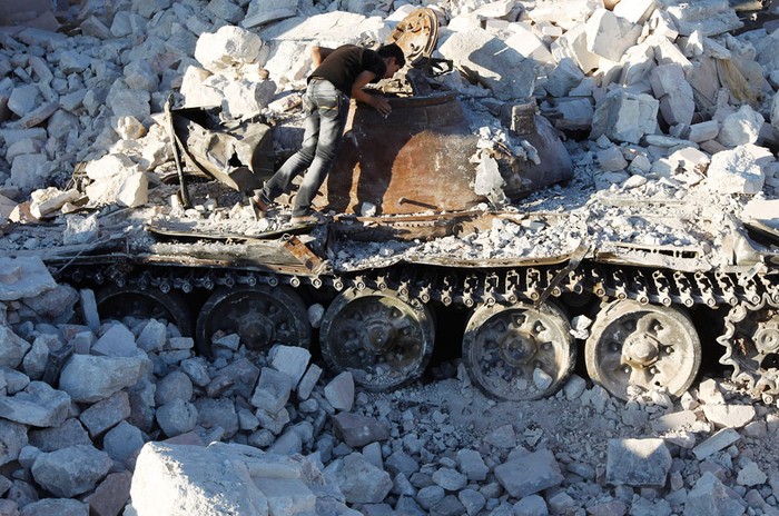 Một người đàn ông Syria đang ngó vào một chiếc xe tăng của quân chính phủ bị bắn hỏng ở Azaz hôm 3/8