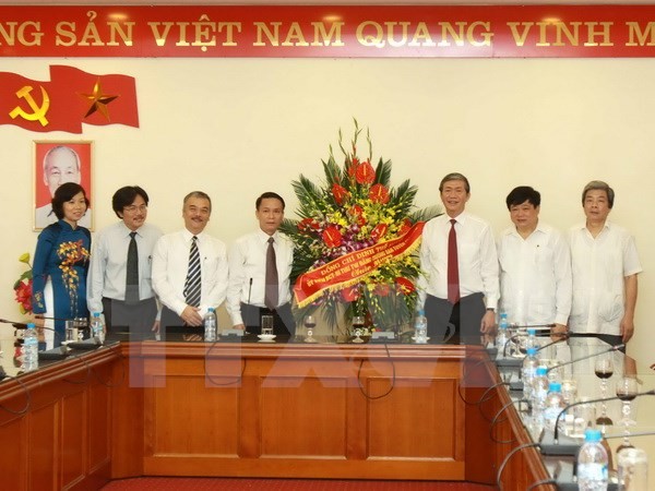 Trưởng Ban Tuyên giáo Trung ương Đinh Thế Huynh tặng lẵng hoa chúc mừng TTXVN. (Ảnh: Minh Quyết/TTXVN)