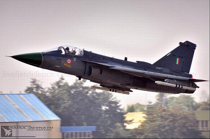 Để đối phó với máy bay chiến đấu F-16 của Không quân Pakistan, thay thế máy bay chiến đấu MiG-21, năm 1983, Chính phủ Ấn Độ phê chuẩn chương trình máy bay chiến đấu hạng nhẹ LCA. Ấn Độ hy vọng thông qua kế hoạch này có thể giúp Ấn Độ có được khả năng tự nghiên cứu chế tạo máy bay tác chiến thế hệ thứ ba. Kế hoạch này nội dung rộng, gồm máy bay, động cơ phản lực, radar điều khiển hỏa lực PD, hệ thống điện tử hàng không số hóa và buồng lái thủy tinh, tên lửa không đối không dẫn đường radar chủ động… Nhưng, thực lực công nghệ công nghiệp hàng không và kinh tế khi đó của Ấn Độ rất khó độc lập hoàn thành chương trình này, cho nên Ấn Độ lựa chọn công ty Dassault Pháp làm đối tác, hỗ trợ công nghệ cho Ấn Độ. Vì vậy, máy bay LCA đã chọn bố cục cánh tam giác không đuôi. Ngoài ra, Ấn Độ còn dựa vào công ty General Electric cung cấp động cơ phản lực F404, công ty Lockheed Martin cung cấp hệ thống điều khiển telex; còn phần mềm của hệ thống điều khiển telex của LCA được thử nghiệm trên máy bay F-16D VISTA của Mỹ.