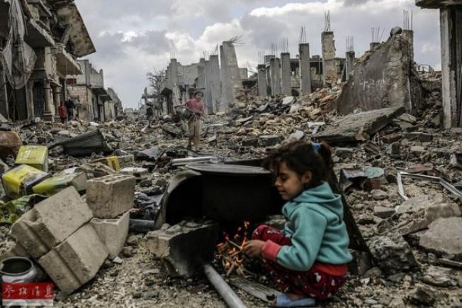 Một bé gái người Kurd nhóm lửa trong đống đổ nát