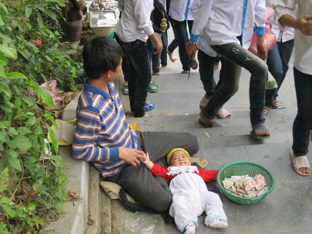 Người đàn ông khỏe mạnh này đem đứa bé 7 tháng tuổi nằm trước cổng chùa Đọi (Hà Nam) để xin tiền. (ảnh: Cao Tuân)