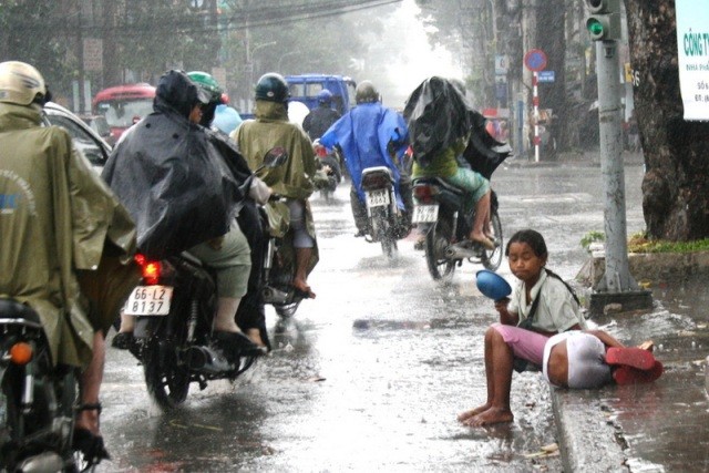 Cái rét xen lẫn những hạt mưa không ngăn được các em mưu sinh, xin ăn giữa đường phố (Ảnh bạn đọc)