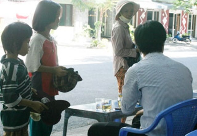 Cái bang” nhí đang xin ăn trên đường Ngô Gia Tự, TP Đà Nẵng bên cạnh một người bán vé số được gọi là mẹ. (Ảnh: Lê Phi)