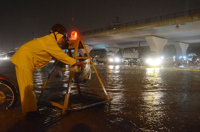 Công nhân của Công ty thoát nước Hà Nội cũng đang làm việc dưới mưa để nước có thể thoát nhanh hơn.