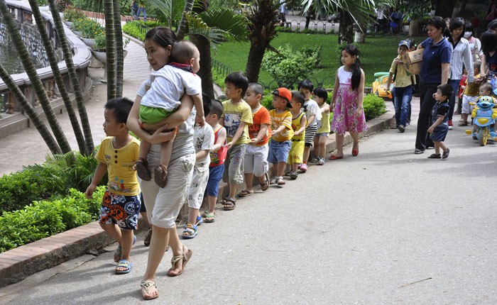 Các bé nhỏ nối đuôi nhau theo cô giáo đi thăm quan.