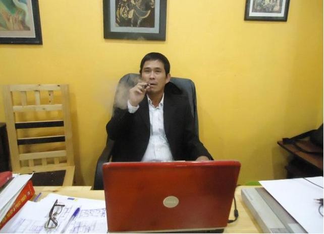 Hình ảnh Anh Thắng ngồi trong phòng làm việc và sử dụng thuốc lá điện tử