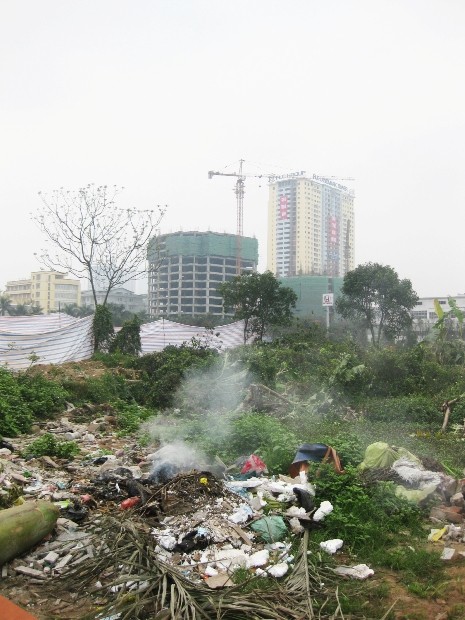 Bên cạnh các tòa nhà cao tầng tiện nghi, hiện đại là một khu đất “ngập ngụa” rác. Thậm chí rác còn được đốt để phân hủy gây ô nhiễm nguồn không khí.