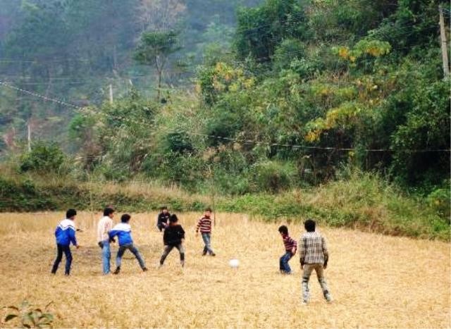 Một trận bóng đá đang diễn ra trên sân vận động giữa núi rừng