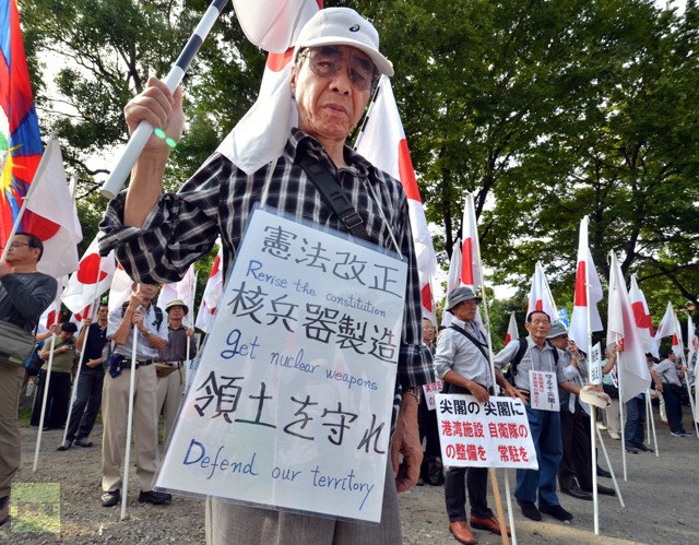 Một cụ già mang theo biểu ngữ "Dùng vũ khí hạt nhân để bảo vệ lãnh thổ"