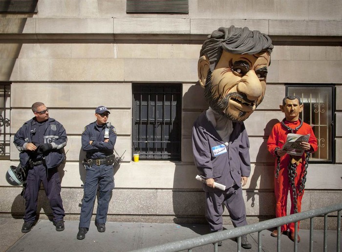 Cảnh sát New York đứng bên cạnh người đàn ông hóa trang thành bộ dạng Tổng thống Iran Mahmoud Ahmadinejad, thứ hai từ bên phải sang và Tổng thống Syria Bashar al-Assad trong bộ áo tù nhân, gông cùm. Đó là một hoạt động nằm trong cuộc biểu tình phản đối hai nhân vật này ở bên ngoài khách sạn Warwick ở thành phố New York vào ngày 25. Ahmadinejad ở tại khách sạn trong chuyến thăm của ông đến New York dự họp Đại hội đồng Liên Hợp Quốc.