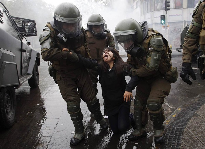 Cảnh sát chống bạo động bắt giữ một sinh viên trong cuộc biểu tình yêu cầu chính phủ thay đổi hệ thống giáo dục công ở Santiago, Chile hôm 27/9. Sinh viên Chile đã xuống đường biểu tình chống lại hành vi mà họ gọi là trục lợi hệ thống giáo dục quốc dân.