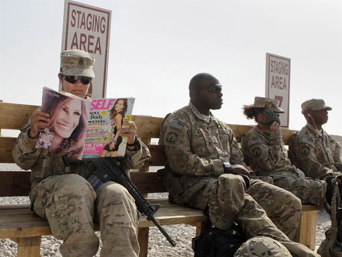 Thượng sĩ Norma Gonzales thuộc Tiểu đoàn 426 phụ trách các vấn đề dân sự đang đọc cuốn tạp chí bên cạnh các đồng đội ở Kandahar, Afghanistan hôm 11/10 trong khi chờ đợi được chuyển tới một căn cứ khác bằng trực thăng.