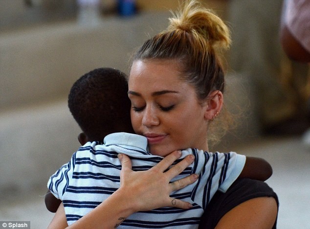 Hình ảnh đáng yêu của Miley khi tới Haiti làm từ thiện, cô âu yếm bế một em nhỏ.