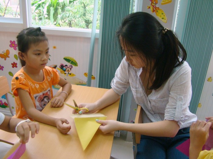 Chị Thanh Hiên giúp đỡ các em nhỏ cắt, gấp giấy. >>BẤM ĐÂY XEM CẬP NHẬT ĐIỂM THI ĐẠI HỌC, CAO ĐẲNG NHANH NHẤT 2012