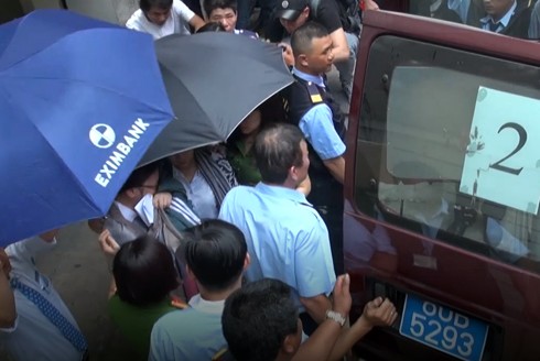 Nhân viên ngân hàng Eximbank bị bắt giữ, áp giải ra xe để về nơi tạm giam. (Ảnh: H.L)