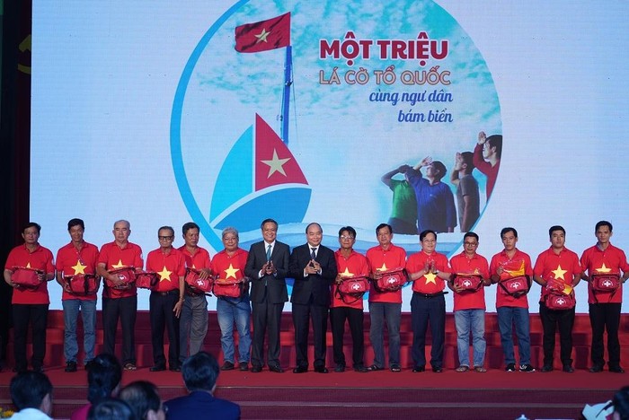 Thủ tướng trao cờ Tổ quốc và túi thiết bị y tế đi biển cho 12 ngư dân trong chương trình “Một triệu lá cờ Tổ quốc cùng ngư dân bám biển”. Ảnh: VGP