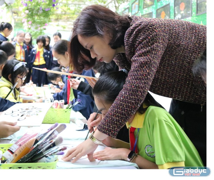 Cô Thạch Thị Thanh Quyên - Chủ nhiệm câu lạc bộ nghệ thuật hướng dẫn các học sinh trải nghiệm sáng tạo nghệ thuật tại gian hàng. Ảnh: Đỗ Thơm
