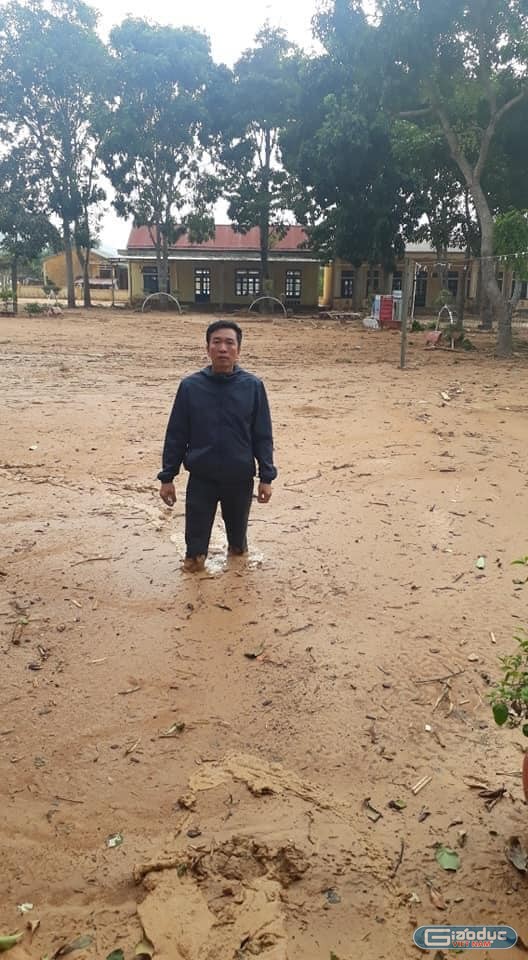 Thầy Nguyễn Văn Tý, hiệu trưởng trường Tiểu học và Trung học cơ sở Hướng Việt đứng gữa sân trường đầy sình, đất gần nửa mét đang vô cùng lo lắng