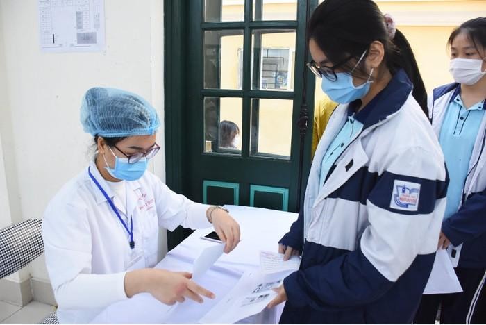 Nhân viên y tế kiểm tra danh sách học sinh đăng ký tiêm (Ảnh: NH)