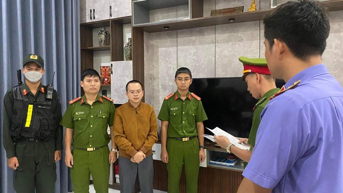 Cơ quan công an đọc lệnh bắt tạm giam đối với Hoàng Quang Huy (áo vàng), Trưởng phòng Kế hoạch - Tài chính của Trường Đại học Bách khoa Đà Nẵng. Ảnh: NAN
