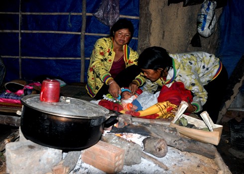 Ngay sau xuất viện về nhà, bé trai con chị Đinh Thị Hoái được sưởi ấm bên bếp lửa tại nhà riêng ở xã Sơn Nham, huyện miền núi Sơn Hà.