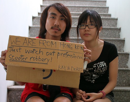 Kay (trái) và Doris phải giữ khư khư bên người tấm biển với dòng chữ tiếng Anh: "Chúng tôi đến từ Hong Kong. Xin hãy cẩn thận với những tên cướp chuyên chạy xe gắn máy".