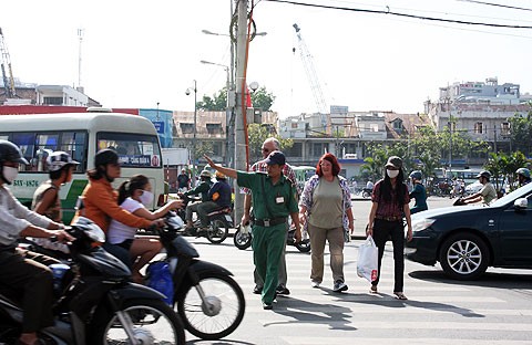 Anh Trần Duy Phong (Dội bảo vệ du khách nước ngoài) đang dẫn khách qua đường. Ảnh: Tá Lâm.