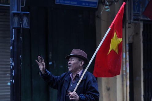 Trên phố bỗng xuất hiện một cụ già cầm cờ đi dạo hát nghêu ngao.