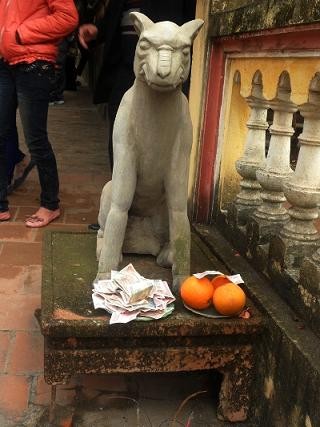 Bức tượng chó đá trước chùa Hồng Ân (chùa Lim, Tiên Du, Bắc Ninh) cũng được khách đi du xuân trẩy hội "hào phóng" dâng lên một đĩa...tiền thật.