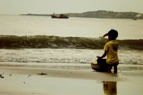 Em bé ngồi bên bờ dõi ánh mắt theo con tàu ra khơi, với lời cầu nguyện cho biển lặng trời yên để cha cậu sớm trở về với thuyền cá đầy khoang.