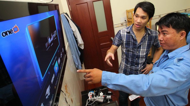 Anh Nguyễn Văn Sở (phải), nhân viên Công ty TNHH MTV Phương Nam (FPT), hướng dẫn khách hàng mới xem OneTV qua đường truyền Internet sau khi lắp đặt xong sáng 25-10 - Ảnh: Như Hùng
