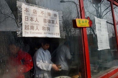 Tấm biển hiệu kỳ thị treo trên cửa sổ của một nhà hàng ở Bắc Kinh được viết song ngữ Hoa – Anh: “Nhà hàng chúng tôi không tiếp nhận người Nhật, Philippines, Việt Nam và chó” - Ảnh: AFP