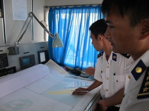 Thuyền trưởng Phạm Nguyên Phú (bên phải) đang cùng đồng đội xem bản đồ, tính toán độ nông sâu của khu vực có tàu cá lạ..
