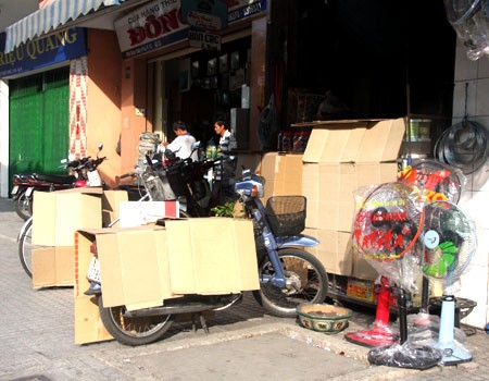 Một cửa hàng trên đường Điện Biên Phủ dùng bìa các tông để che nắng cho xe máy và tủ trưng bày hàng hóa. Ảnh: VnExpress