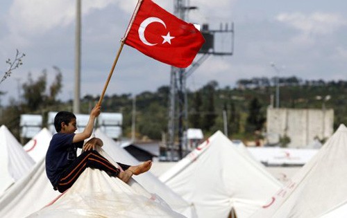 Một người tị nạn Syria cắm lá cờ Thổ Nhĩ Kỳ lên nóc trại tị nạn Reyhanli, Hatay. Ảnh: Reuters.