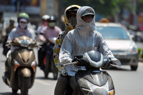 Hầu hết người đi xe máy đều phải trùm kín với áo chống nắng, khẩu trang.