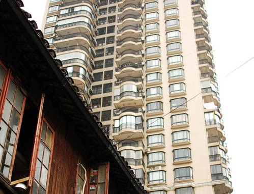 Một mái nhà kiểu truyền thống nằm cạnh một khu căn hộ cao tầng.