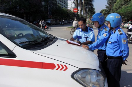 Thanh tra Giao thông (Sở Giao thông Vận tải Hà Nội) xử lý lỗi vi phạm đón khách không đúng nơi quy định trên đường Kim Đồng (quận Hoàng Mai) của Hãng taxi Group. Ảnh: Thế Duyệt/ TTXVN.