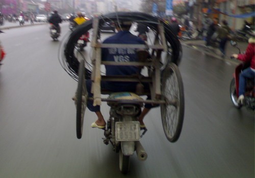 Dùng xe máy chở cả cuộn thép và chiếc xe, chụp tại đường Tây Sơn, Hà Nội. Ảnh: Thiên Hải.