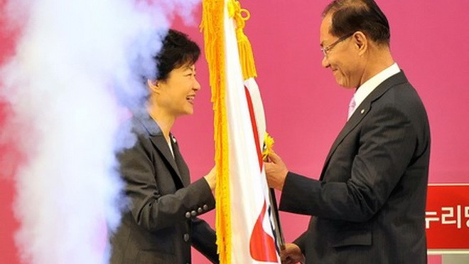 Bà Park Geun Hye trao lại lá cờ của Đảng Saenuri cho lãnh đạo mới, ông Hwang Woo Yea. Ảnh: Reuters.