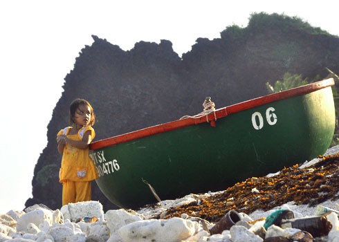 Bé gái ở xã An Bình (đảo Bé), huyện đảo Lý Sơn, đứng trên bờ chờ đợi cha mẹ đi biển về trong hoàng hôn buông xuống.
