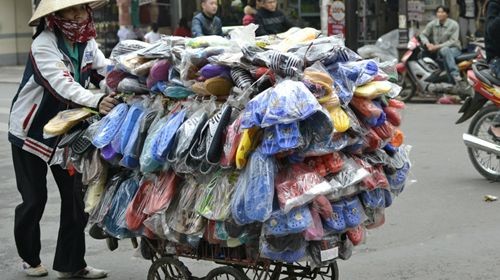 Người phụ nữ bán dép dạo ở phố cổ Hà Nội - không phải là nơi khô ráo nhất Việt Nam - vất vả lo toan để những đôi dép của mình không bị ướt.