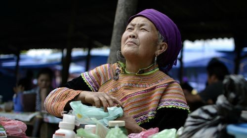 Người phụ nữ H'mong với chiếc áo thổ cẩm sặc sỡ này đang bán thuốc thảo dược ở chợ Bắc Hà, miền Bắc Việt Nam, gần biên giới với Trung Quốc.