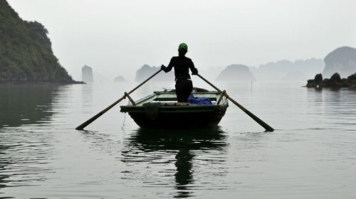 Dáng người phụ nữ chèo thuyền đưa đón khách du lịch đi tham quan các khu làng nổi trên Vịnh Hạ Long.