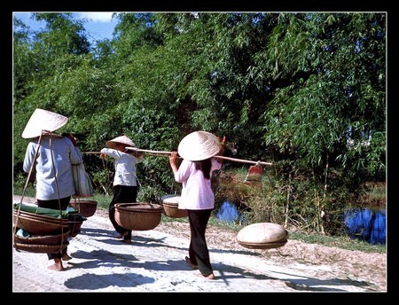 Những người phụ nữ Việt Nam đang trở về nhà từ khu chợ trong làng Thủy Phú.