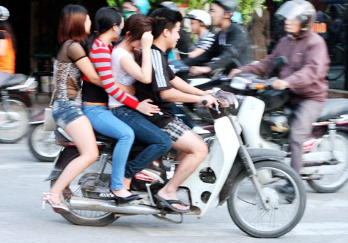 Bốn người không đội mũ bảo hiểm ngồi trên chiếc xe máy. Chụp trên đường Kim Ngưu - Hà Nội. Ảnh: Hoàng Anh Dũng.