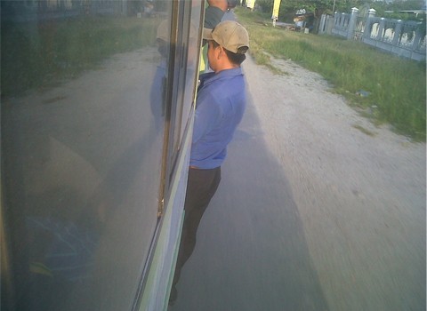 Xe buýt chở quá nhiều người nên nhân viên xe buýt không còn chỗ đứng, phải đu ngoài cửa. Hình ảnh tại tỉnh lộ 943, huyện Thoại Sơn, An Giang. Ảnh: Dương Hữu Trung.