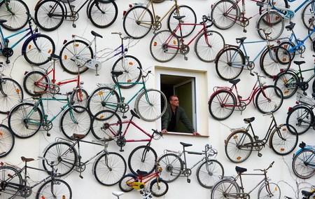 Người đàn ông bên cửa sổ của một cửa hàng bán và cho thuê xe đạp ở Atlandsberg, Đức, được trang trí với hàng trăm chiếc xe đạp trên tường.
