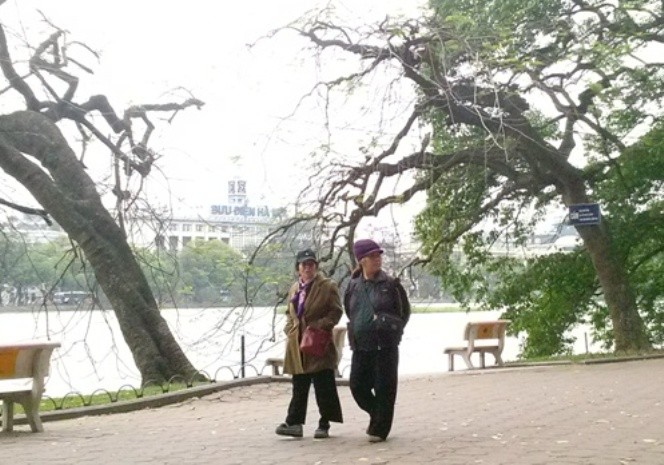Hai người phụ nữ áo choàng, khăn ấm đi dạo quanh Hồ Gươm sáng nay 12-4